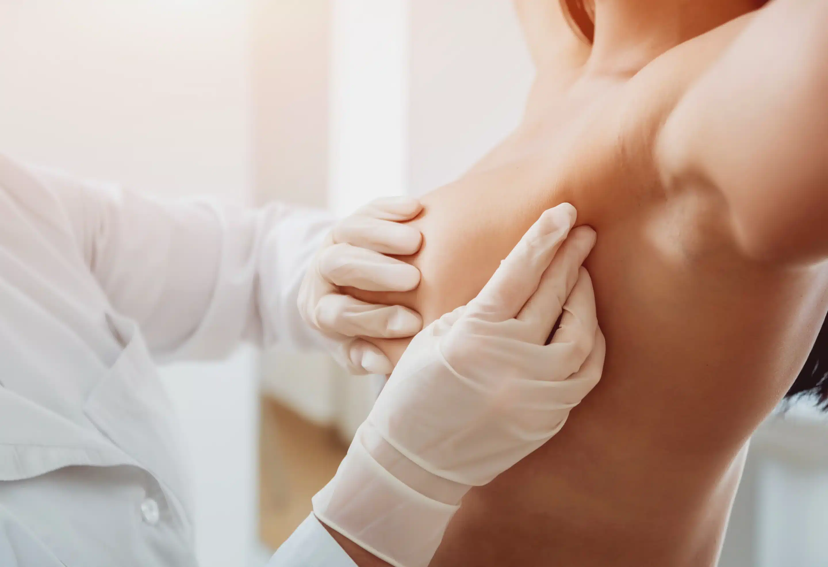 Doctor get examining breast of young woman.
